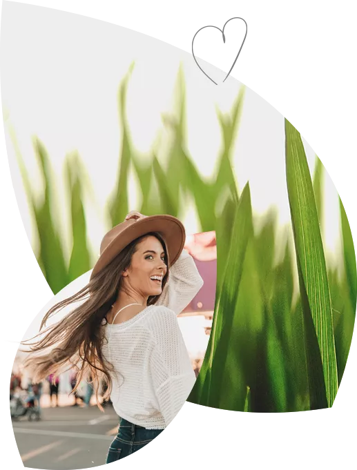 Źdźbła trawy w zbliżeniu makro, niedobór magnezu zwiększa podatność na stres i może skutkować uczuciem zmęczenia. Uśmiechnięta kobieta w kapeluszu. W czym pomaga magnez? Magnez pomaga na skurcze mięśni, na stres i na nerwowość.