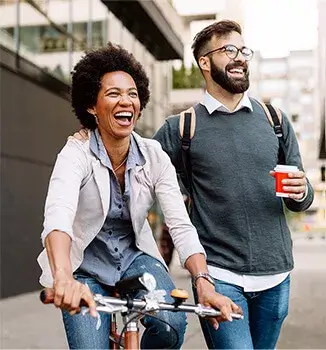Szczęśliwa kobieta na rowerze, obok idzie mężczyzna z kubkiem kawy; Essentia Proactive kupisz w aptece internetowej Melissa
