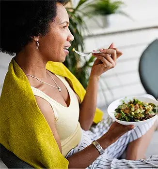 Kobieta na krześle, je sałatkę warzywną; odpowiednia dieta jest ważna dla wątroby, Essentiale Proactive również proaktywnie wspiera wątrobę.