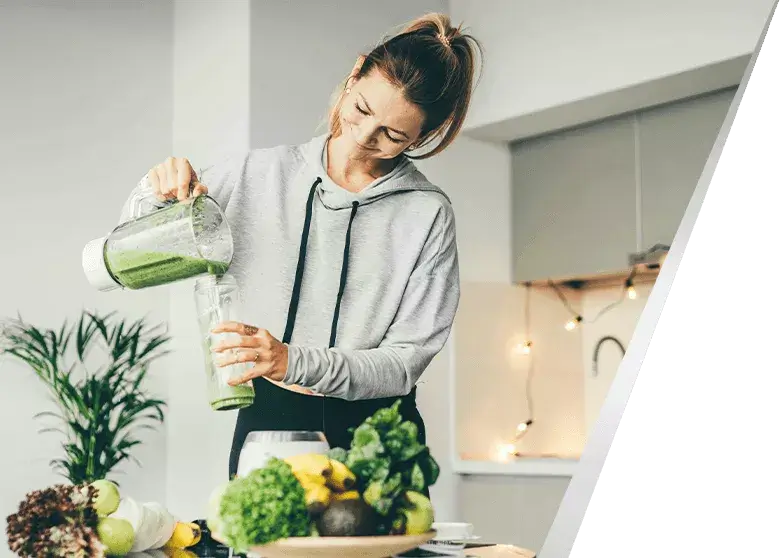 Kobieta w kuchni nalewa zielone smoothie do bidonu; również suplement diety Essentia Proactive proaktywnie wspomaga wątrobę na co dzień.
